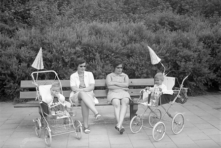 810995 Afbeelding van twee moeders met hun peuters in een kinderwagen, zittend op een bankje in het Ridderplantsoen te ...